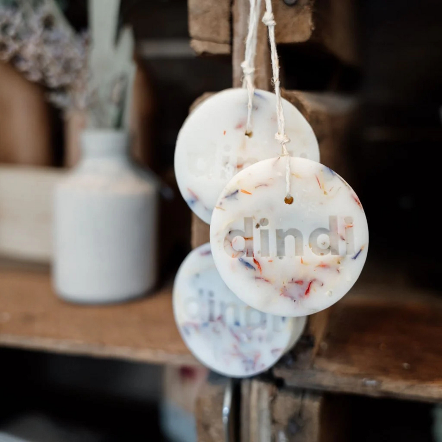 Three wax clothing protectors hanging with vase in the background