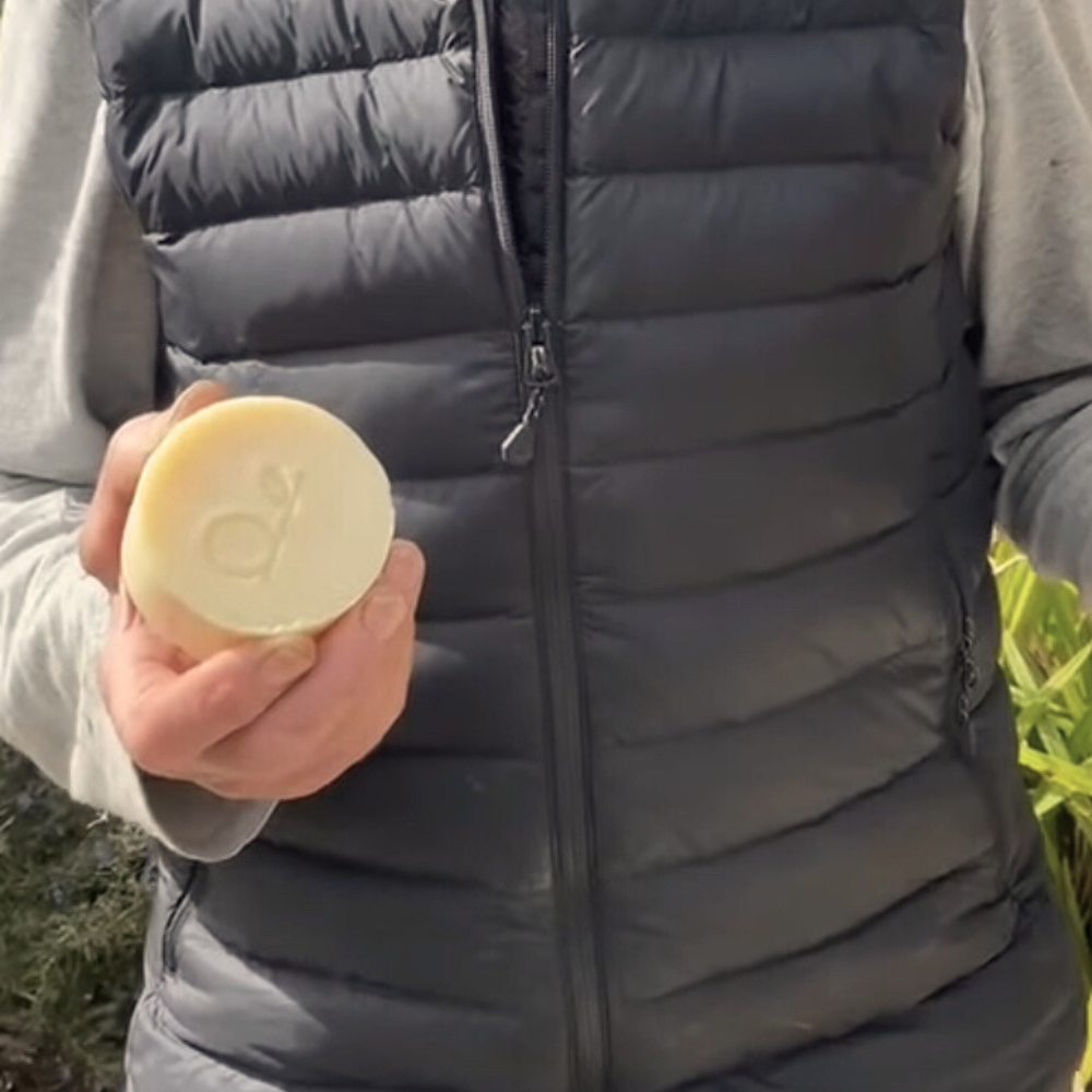 Person holding a yellow bar of soap outdoors