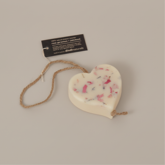 Heart-shaped scented wax with a rope and a label on a beige background