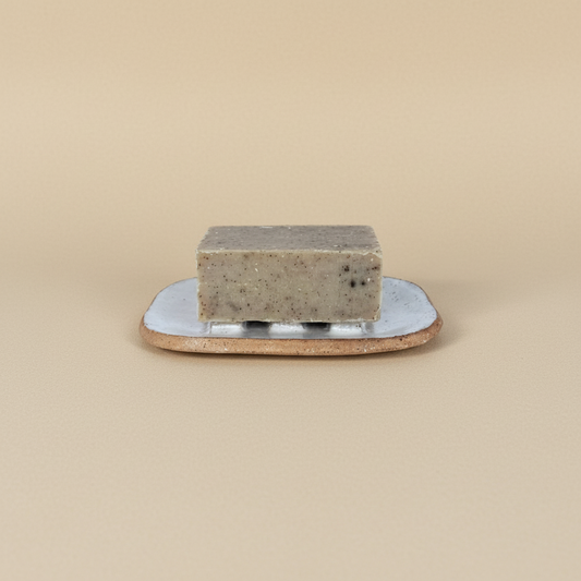 Bar of soap on a ceramic plate against a beige background