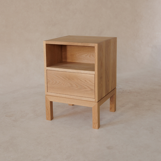 Wooden bedside table with a drawer on a beige background