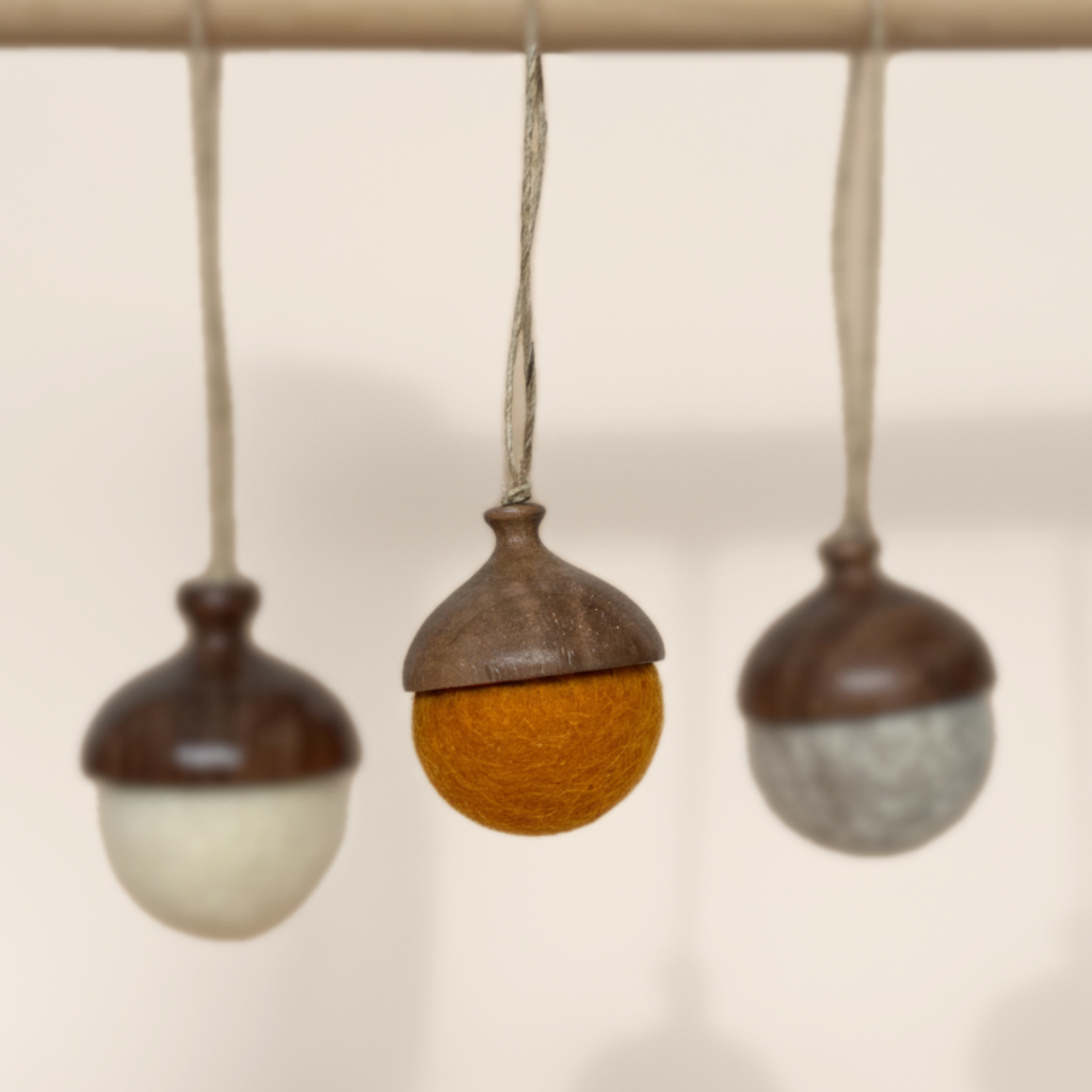 Three hand turned walnut and felt acorn ornaments with jute loop hanging from a wooden stand. Australian Made natural Christmas decoration for slow living