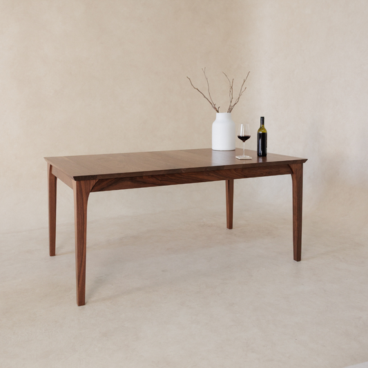 Wooden dining table with a vase and wine bottle on a beige background