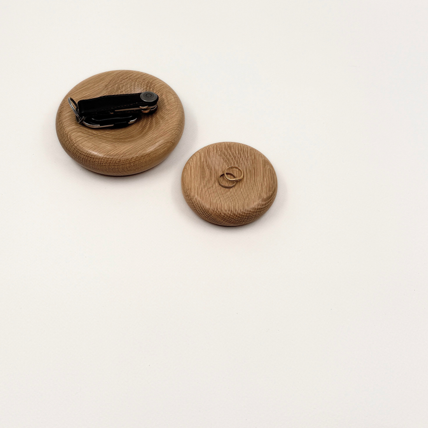 Two wood decorative pillows in small and medium sizes with keys and rings sitting on them. The bowls are made from oak.