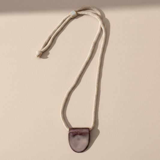 Necklace with a mulberry purple pendant on a beige background