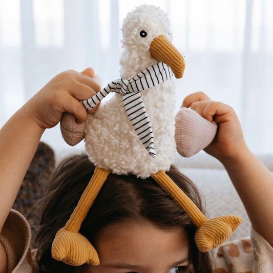 Child holding a plush duck toy on their head with a blurred background