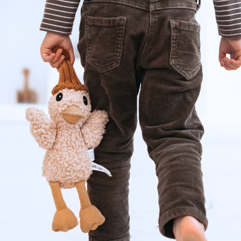 Child holding a knitted duck toy with a blurred background