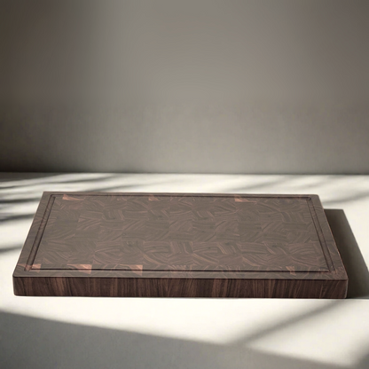 A handcrafted end-grain walnut chopping block with a figure walnut grain pattern, displayed on a kitchen counter with a shadow cast over it.