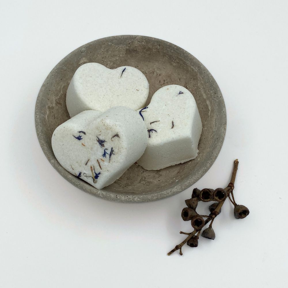 Heart-shaped bath bombs on a stone plate on a white background