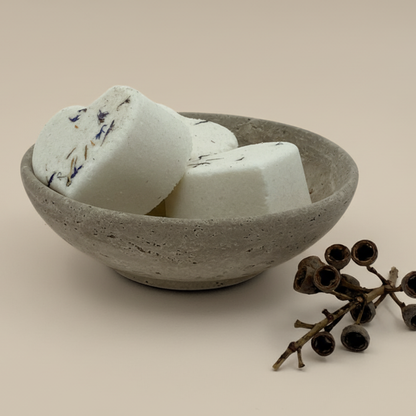 Bath bombs in a concrete bowl on a neutral background
