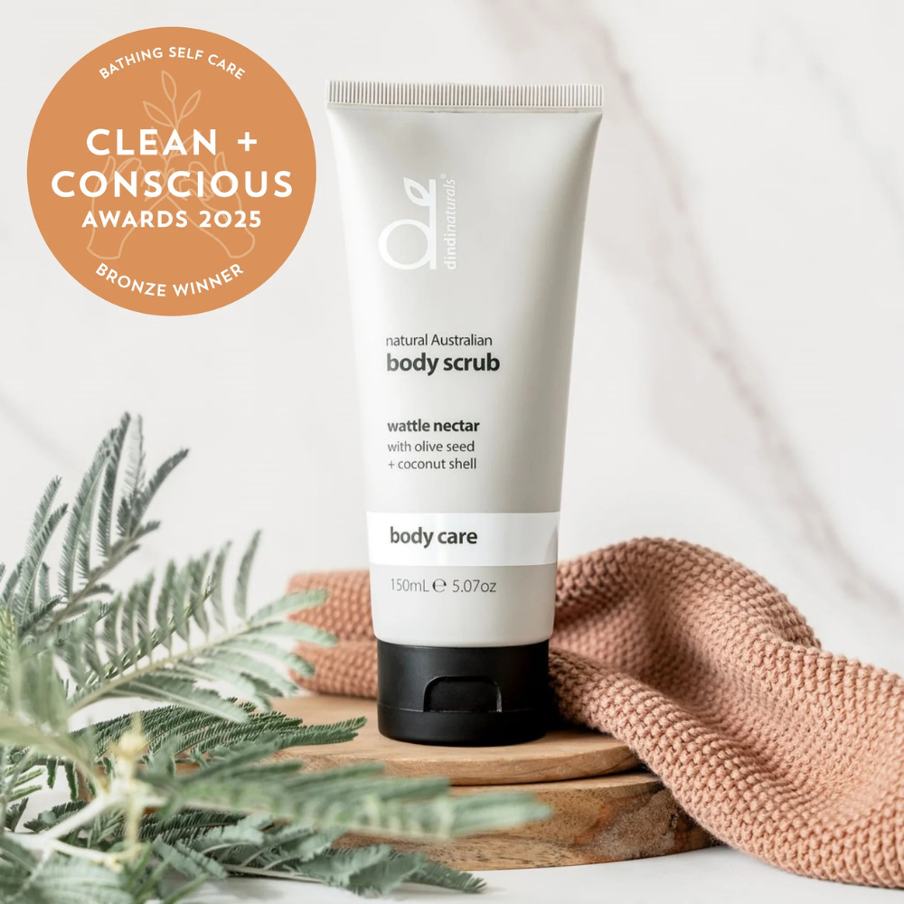 Bottle of body scrub styled with a towel and leaves