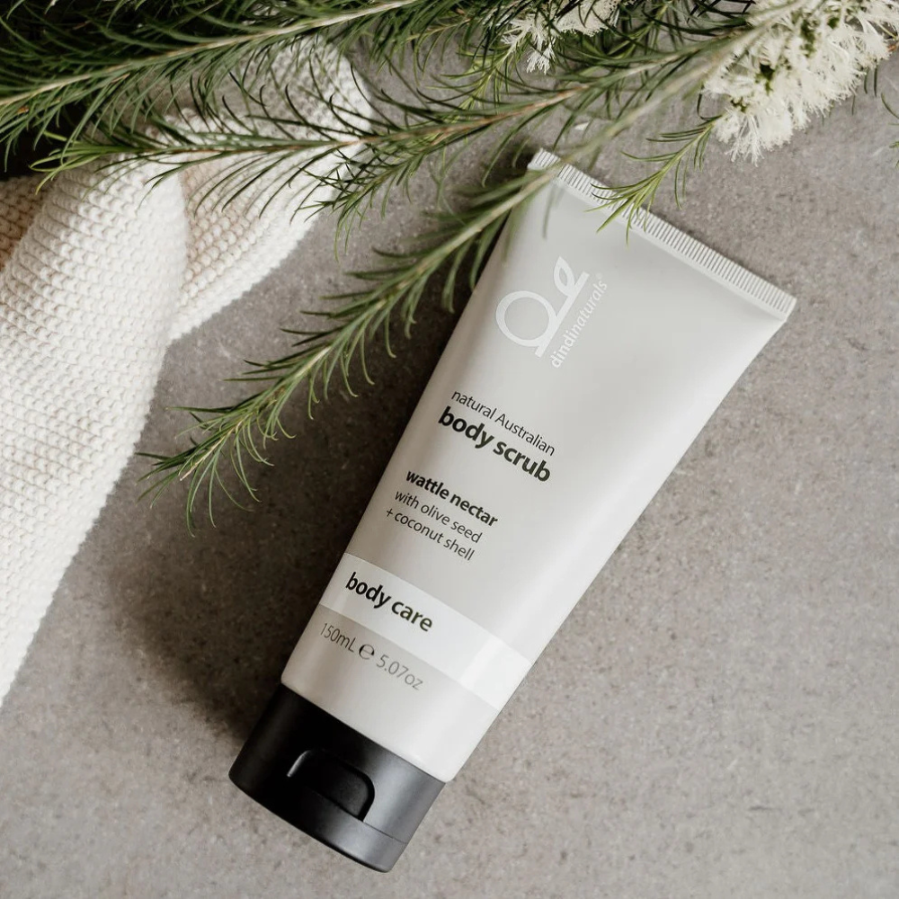 Bottle of body scrub styled with a towel and plants