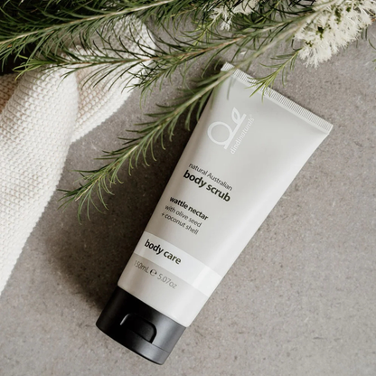 Bottle of body scrub styled with a towel and plants