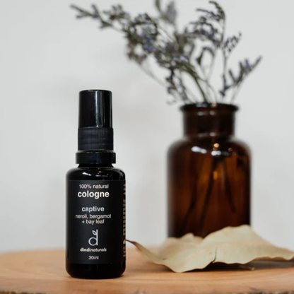 Black cologne bottle labelled 'captive' on a wooden surface with a blurred background