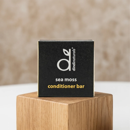 Dindi Naturals Sea Moss Conditioner Bar packaging on a wooden stand with a beige background