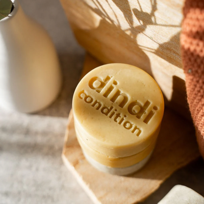 Dindi Naturals Conditioner Bars stacked on top of each other on a wooden surface.