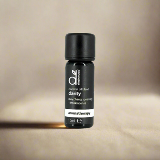 Black essential oil bottle labelled 'clarity' on a beige background