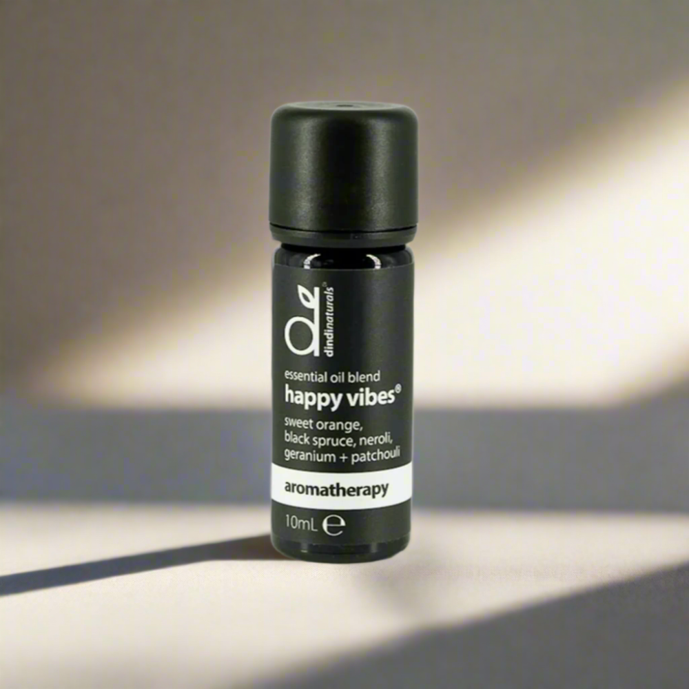 Black essential oil blend bottle labelled 'happy vibes' on a grey background
