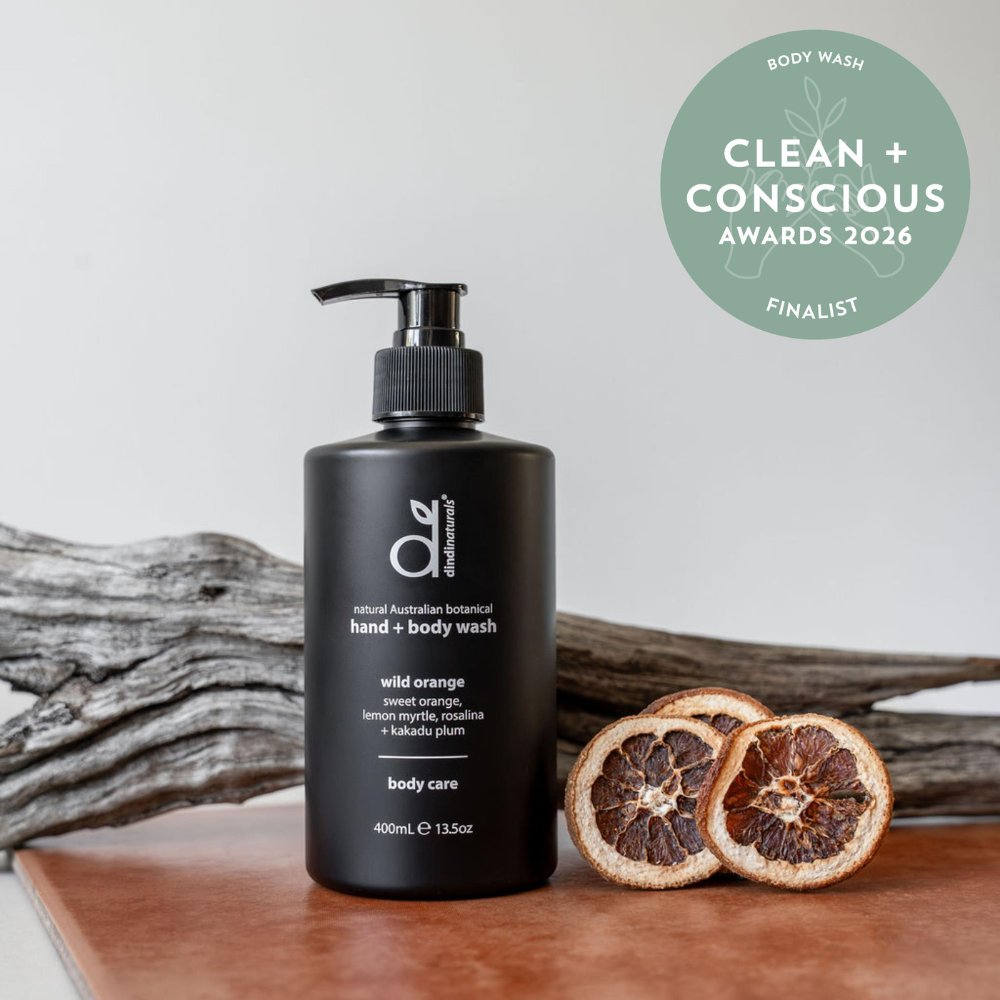 Black hand and body wash bottle with pump on a wooden surface, featuring 'Clean + Conscious' awards badge.