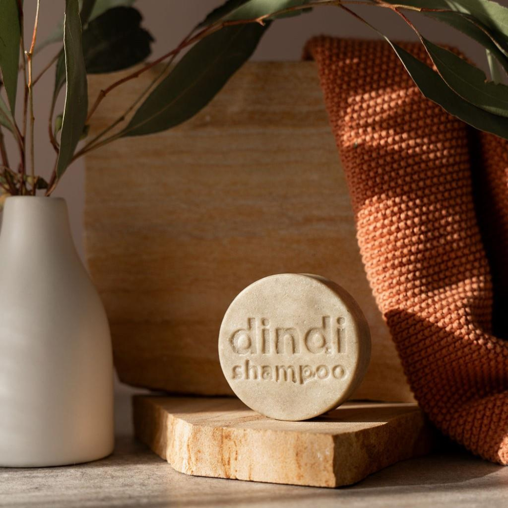 Bar of Dindi Naturals shampoo on a stone block with a textured brown background