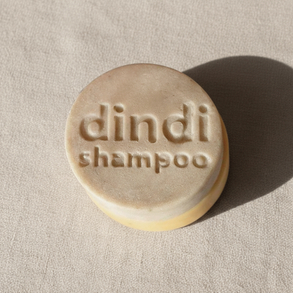 Bar of Dindi Naturals shampoo on a beige fabric background