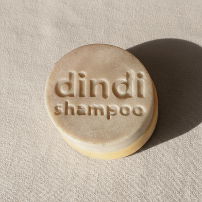 Bar of Dindi Naturals shampoo on a beige fabric background