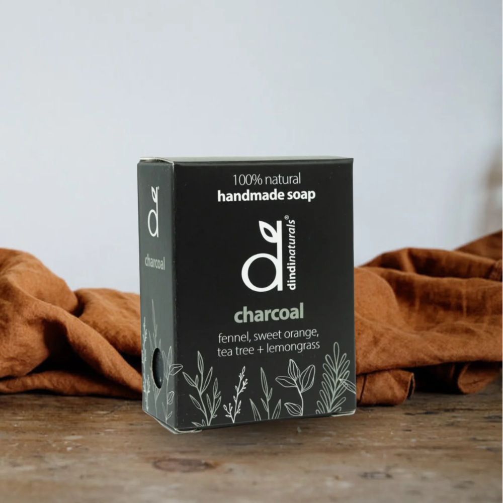 Box of handmade charcoal soap with a natural design on a wooden surface.