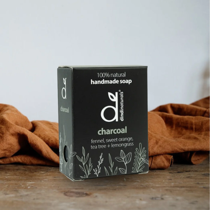 Box of handmade charcoal soap with a natural design on a wooden surface.
