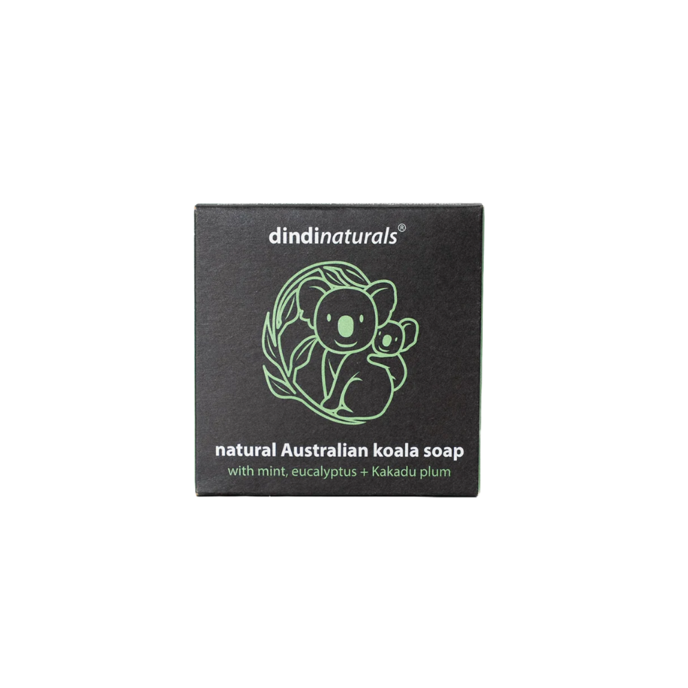 Square black soap packaging with 'dindi naturals' branding and a green koala illustration on a white background.