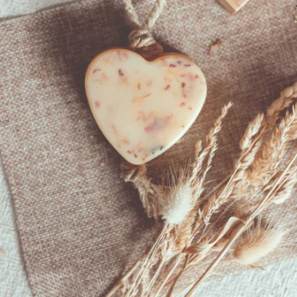 Heart-shaped wax on a rope with wheat stalks on a textured fabric background