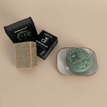 Two bars of soap and their packaging and a soap dish on a beige background