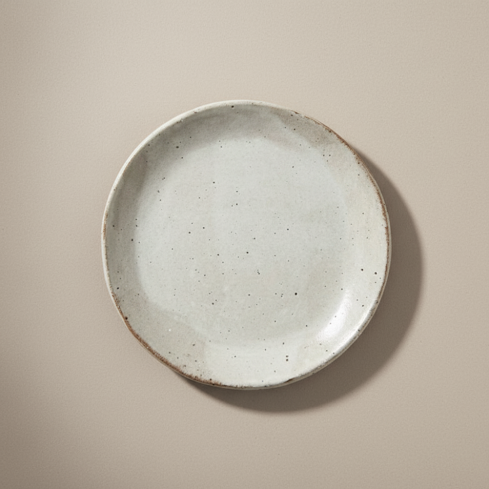 Speckled ceramic plate on a beige background