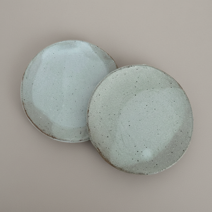 Two ceramic plates with a speckled texture on a beige background
