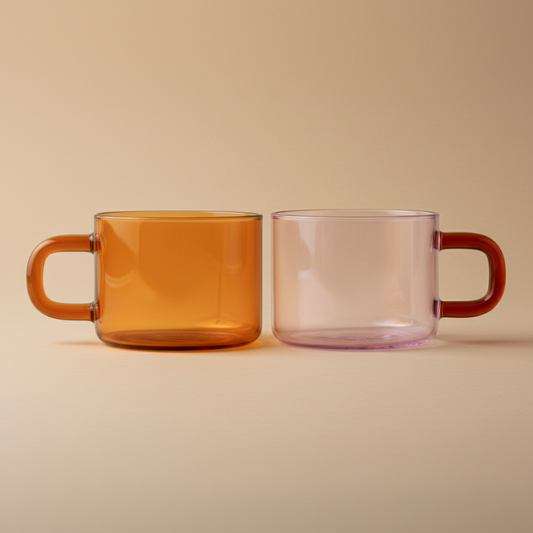Two glass mugs, one orange and one pink, on a beige background
