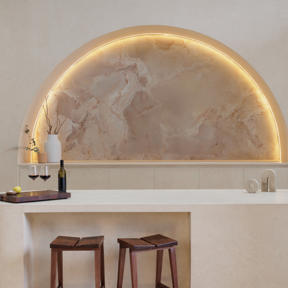 Modern kitchen with marble backsplash and wooden stools. Two travertine sculptures on benchtop with chopping board