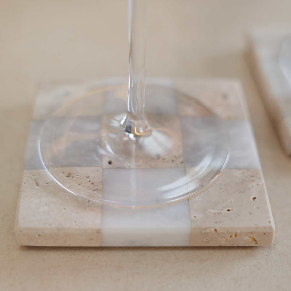 Wine glass on a square stone coaster with a neutral background