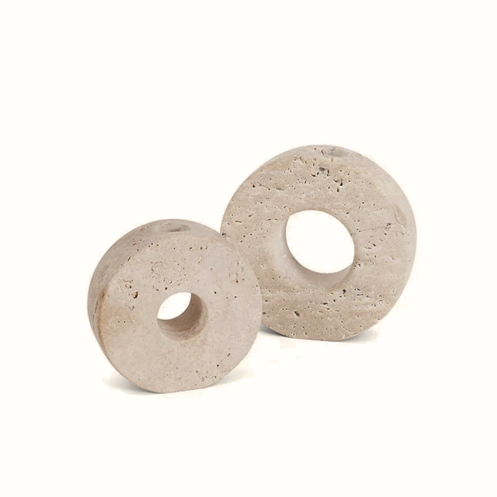 Two beige travertine candle holders with circular holes on a white background