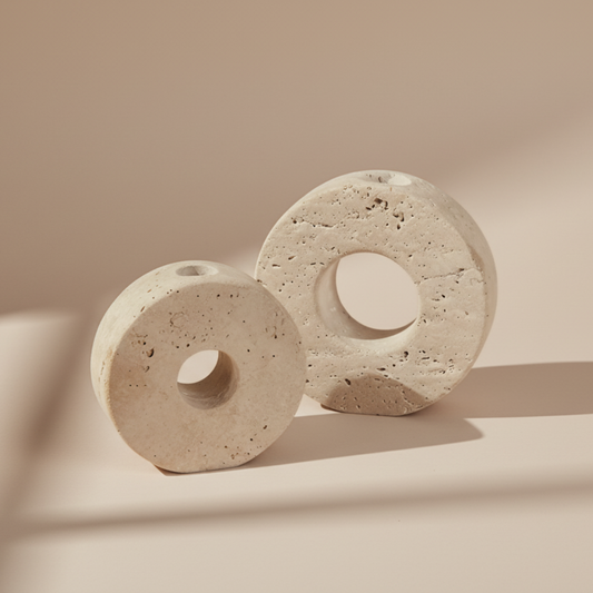 Two beige stone candle holders with circular holes on a beige background