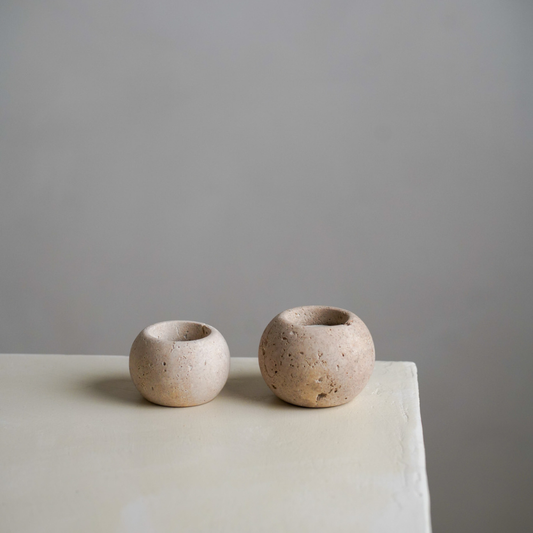 Two travertine candles on a stone bench