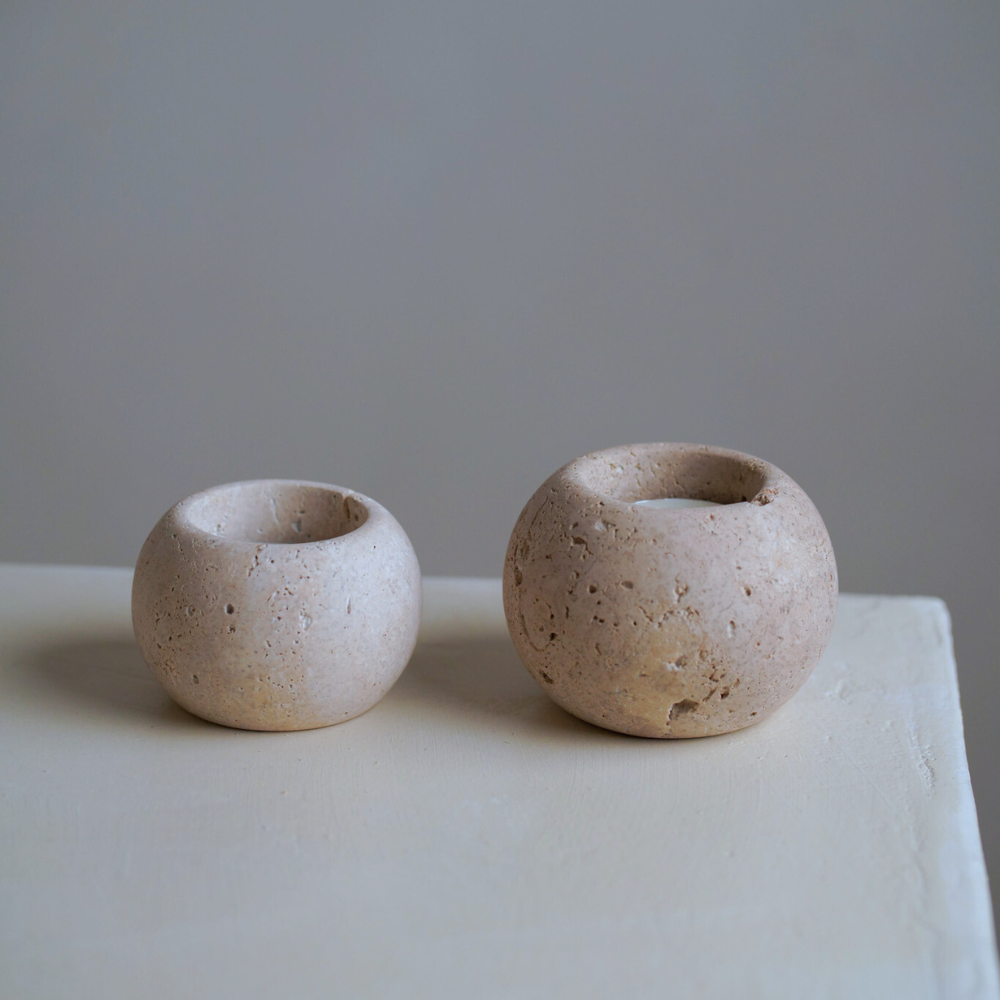 Two travertine candles on a stone bench with a neutral background
