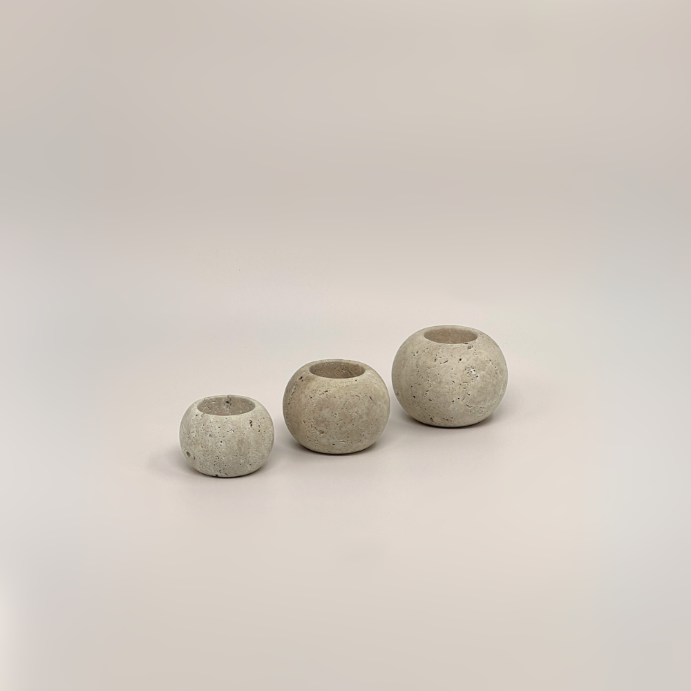 Three travertine candle holders of different sizes on a white background