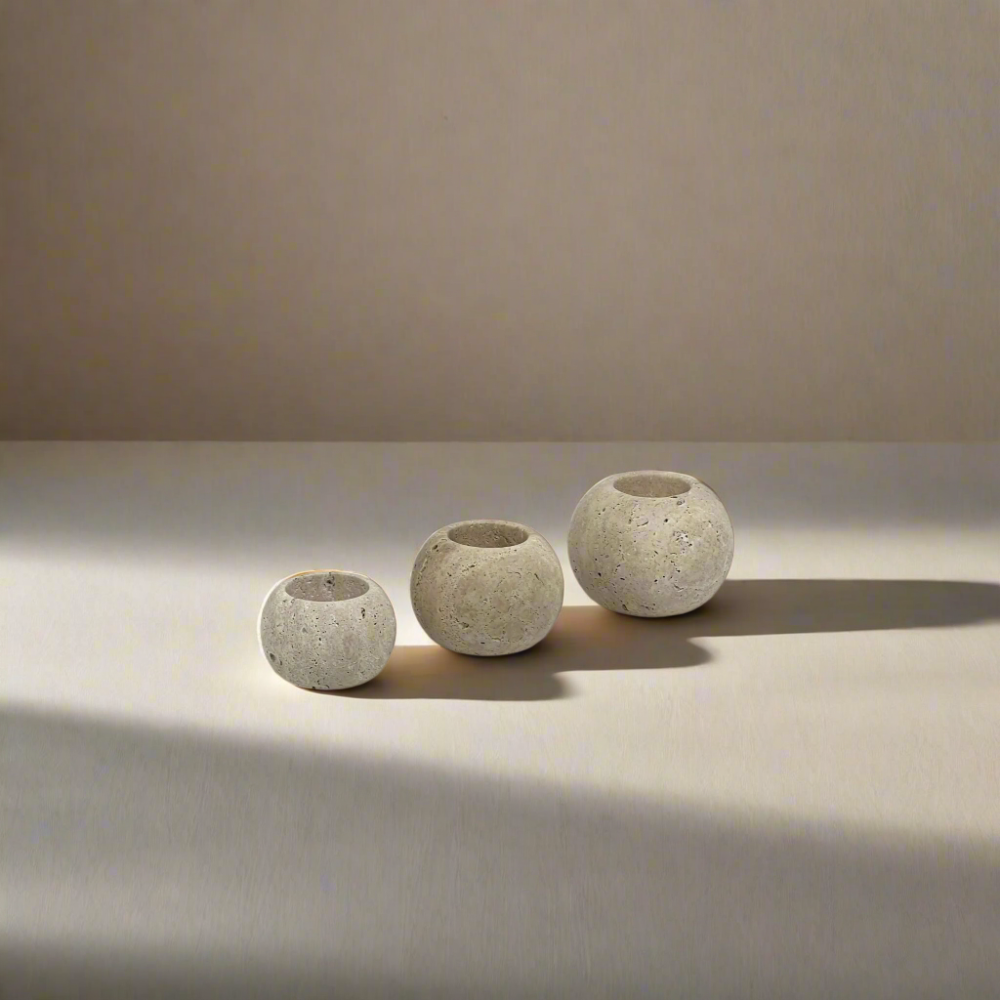 Three travertine candle holders on a stone bench