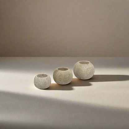Three travertine candle holders on a stone bench