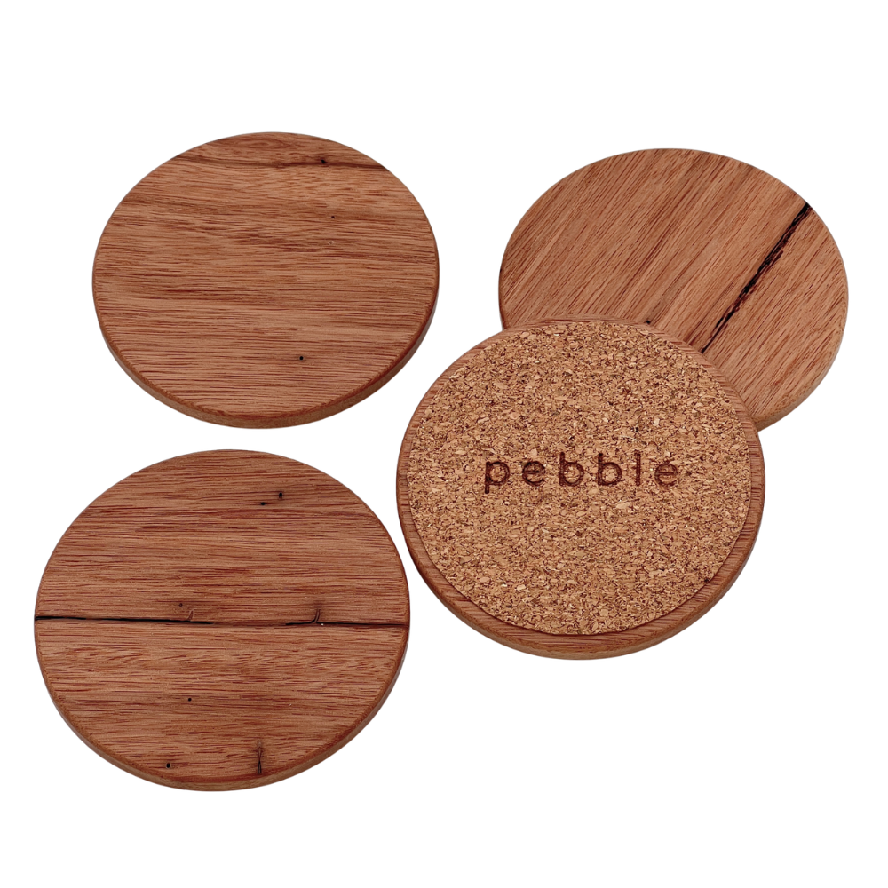 Four wooden coasters with cork bottom, branded 'pebble', on a white background