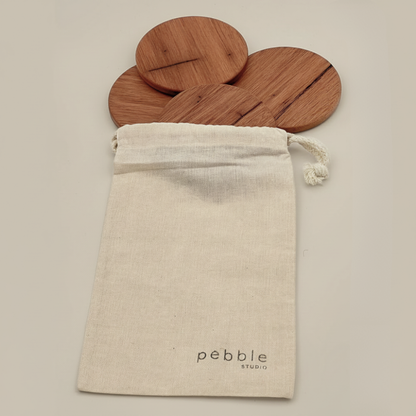 Wooden coasters in a drawstring bag with 'Pebble Studio' branding on a beige background