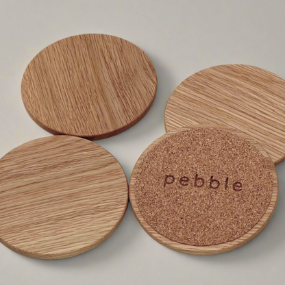Set of wooden coasters with cork bottom, one displaying 'pebble' branding.