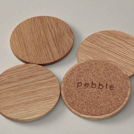 Set of wooden coasters with cork bottom, one displaying 'pebble' branding.