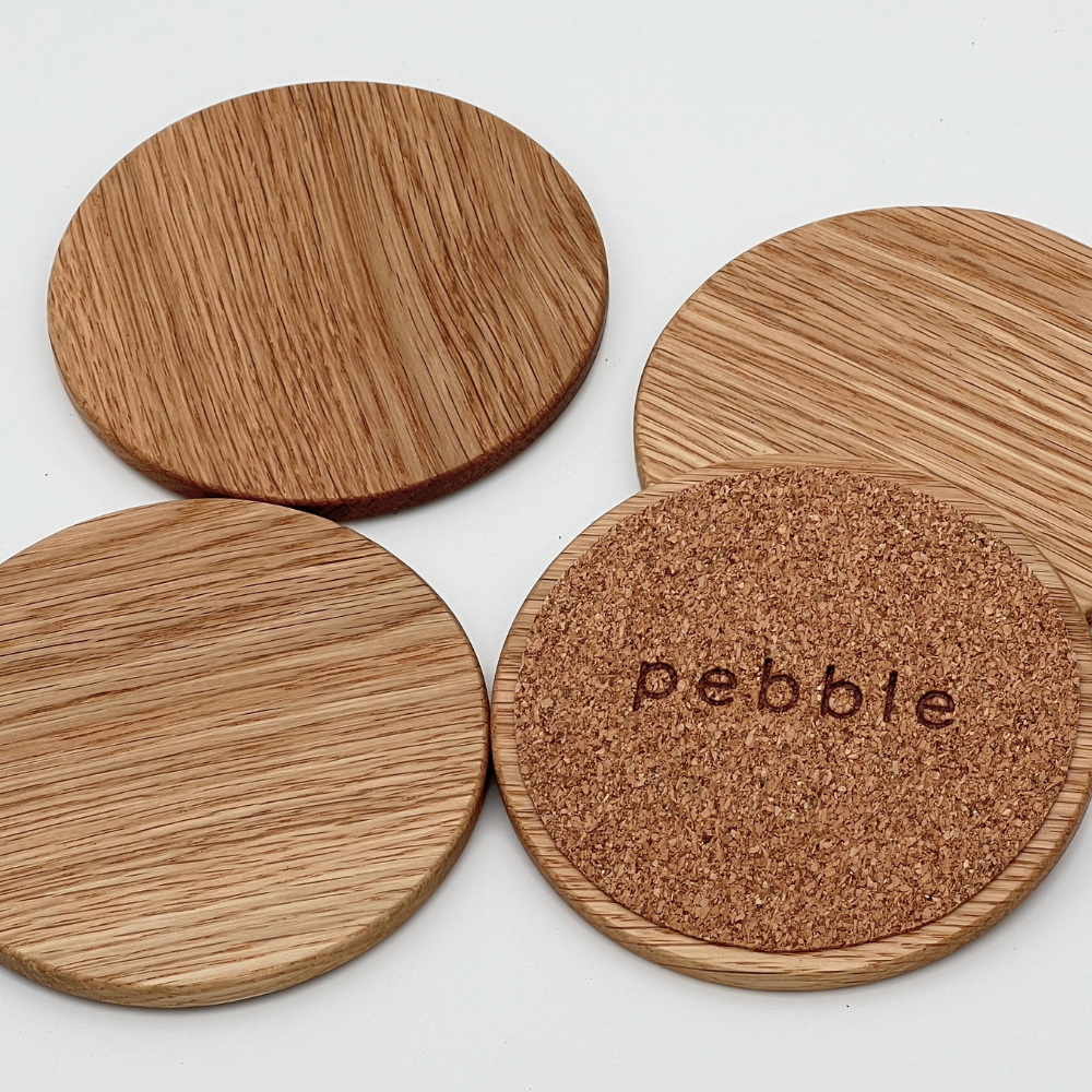Four wooden coasters with cork bottom, embossed with 'Pebble'.