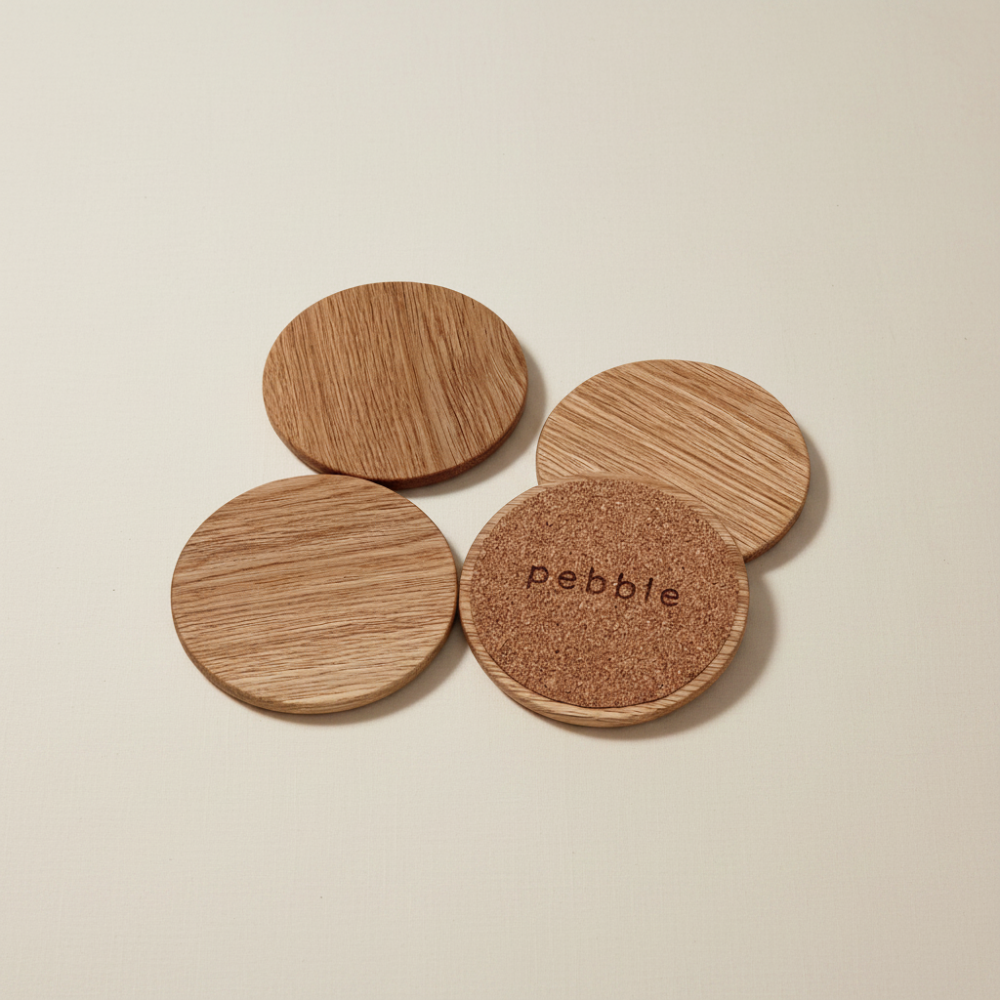 Four wooden coasters on a beige background, with 'pebble' branding.
