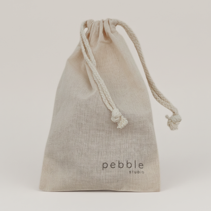 Beige drawstring bag with 'pebble studio' logo on a light background